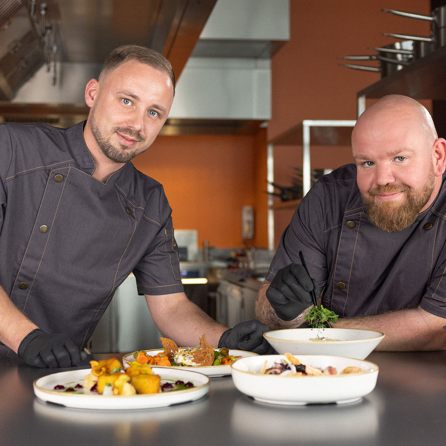 Zwei Köche in der Küche mit angerichteten Tellern auf dem Tresen