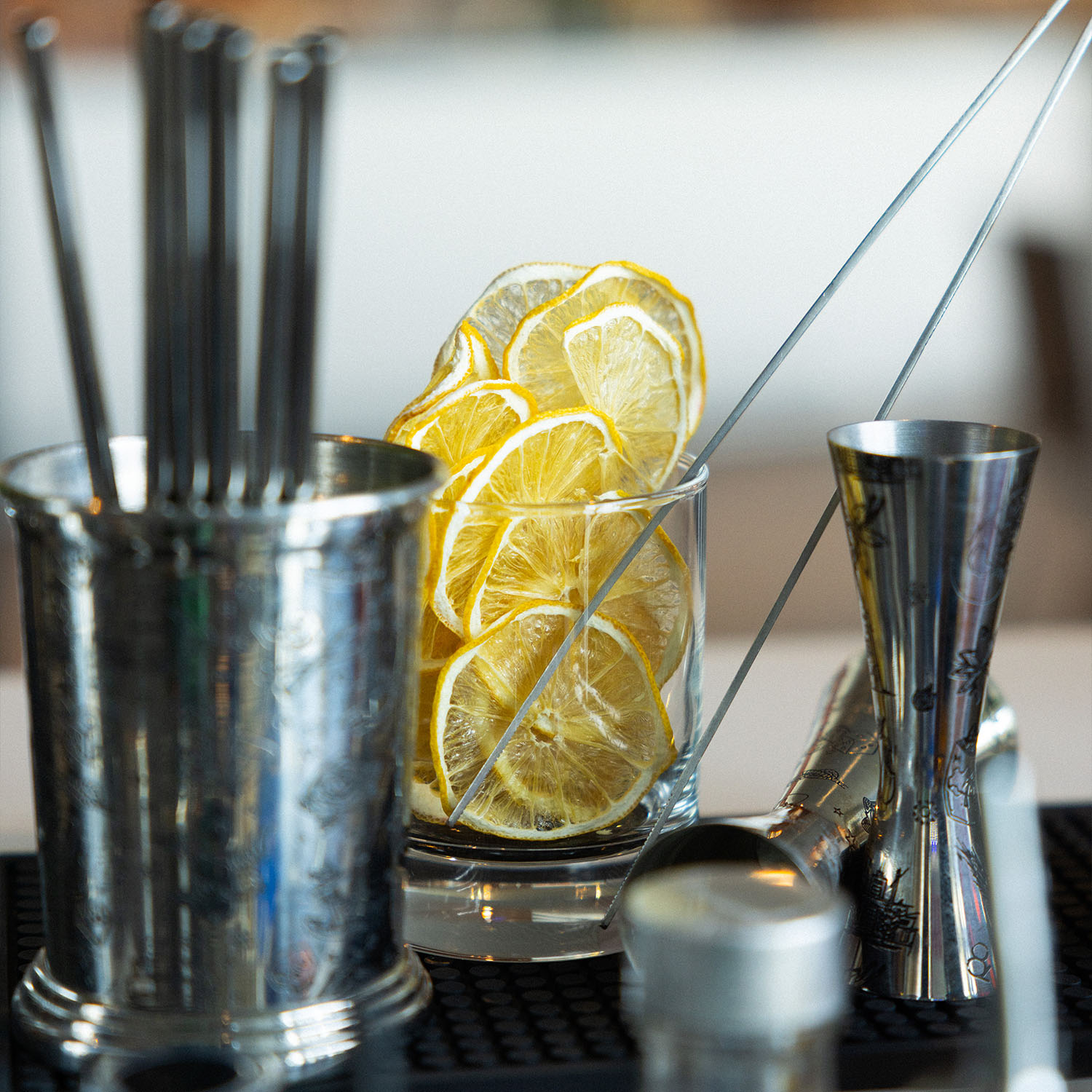 Bar-Detail mit Cocktailzubehör, Metallbecher und Glasgefäß mit Zitronenscheiben