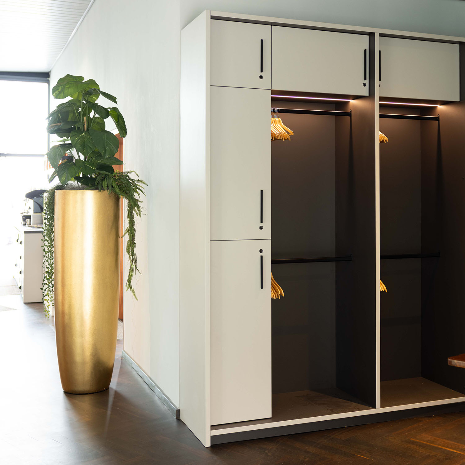 Heller Flur mit hoher goldener Vase und Zimmerpflanze neben Garderobenschränken